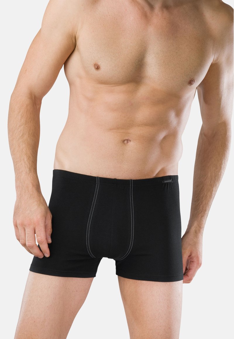 Czarne bokserki z elastycznym pasem, o gładkiej fakturze, z kontrastującym białym przeszyciem z przodu, dopasowany krój i długość do połowy uda.