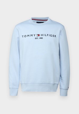 Šviesiai mėlynas ilgarankovė su apvalia iškirpte džemperis su išsiuvinėtu užrašu „Tommy Hilfiger EST. 1985“ ir logo ant krūtinės.