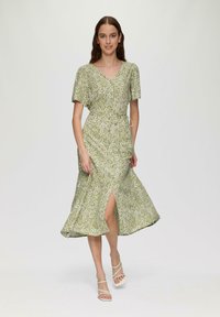 Grünblumiges Wickelkleid mit kurzen Ärmel, V-Ausschnitt, Tailleng�ürtel und vorderem Schlitz. Glatter Stoff mit fließender Silhouette. Weißes Blumenmuster.