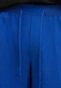 Blå shorts med en strukturerad väv, elastisk midja och långa dragsnören. Inga fickor är synliga på bilden.