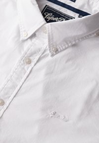 Witte button-up shirt met een klassieke kraag, van katoen met een subtiele textuur. Bevat een klein geborduurd logo op de borst.