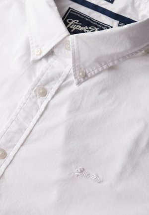 Witte button-up shirt van katoen met een klassieke kraag, voorzien van een klein geborduurd logo op de borst en parelachtige knopen.