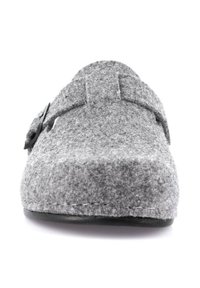 Pantofola grigia in feltro con punta arrotondata, cinturino regolabile e accessori neri. Tessuto morbido con suola piatta nera.