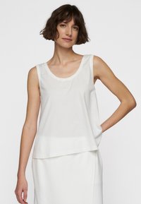 Top bianco senza maniche realizzato in morbido cotone, con scollatura rotonda e vestibilità comoda. Presenta un discreto dettaglio del logo vicino al petto.