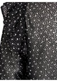 Sort og hvid polka-dots bluse lavet af gennemsigtigt stof, med rynkede detaljer på den ene side og varierende dotstørrelser overalt.