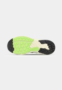 Shoe outsole featuring a textured design with a honeycomb pattern in green and black, complemented by a cream-colored edge.