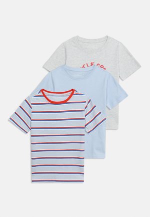 Tre T-shirts med korte ærmer: forstykke med blå, rød og hvid striber og røde kanter, midterstykket ensfarvet lyseblåt, bagsiden lysegrå med delvist synlig rød tekst.
