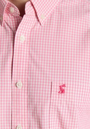 Rosa-weiß kariertes Hemd mit Knöpfen und einer Brusttasche, die ein kleines, rosa gesticktes Kaninchen-Logo zeigt.