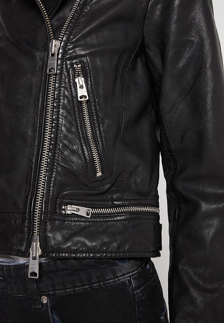 Giubbotto in pelle nera con numerosi zip in argento, design corto e finitura testurizzata sulle maniche, con due tasche anteriori con zip.
