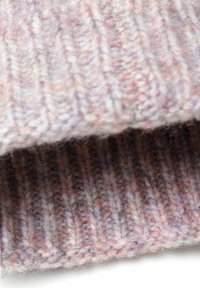 Gestrickter Wollstoff in hellrosa und lavendelfarbenen Nuancen, mit ribbeliger Textur. Die Nahaufnahme zeigt miteinander verflochtene Stränge unterschiedlicher Dicke.