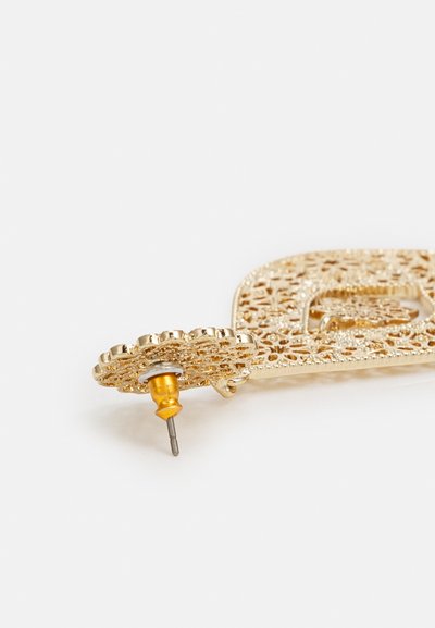 Gold-toned earring featuring intricate lace-like design, with a yellow backing for secure fastening. The overall shape is ornate and flat.