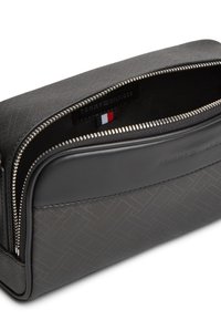 Μαύρο υφασμάτινο νεσεσέρ με φερμουάρ, με το λογότυπο Tommy Hilfiger και λεπτομέρεια με τη σημαία σε κόκκινο, άσπρο και μπλε χρώμα μέσα στον ανοιχτό κύριο θάλαμο.