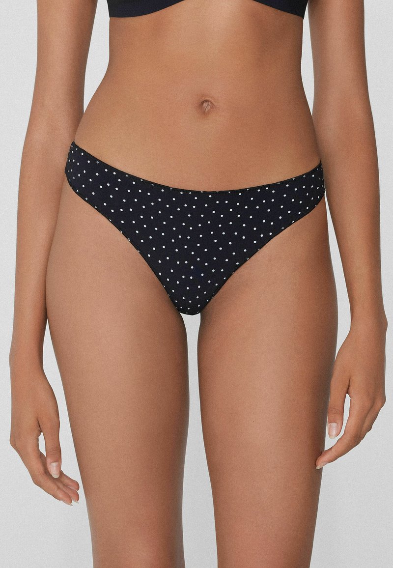 Czarne majtki bikini z wzorem w kropki, elastycznym paskiem w talii i wysokim krojem nogawek, zapewniające minimalistyczny design i dopasowany krój.