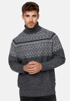 Suéter de cuello alto grueso en negro y gris, con un patrón geométrico en el pecho y tejido de punto texturizado.
