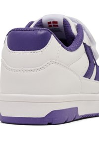 Białe sneakersy z fioletowymi akcentami, teksturowana cholewka, zapięcie na rzep oraz wyściółka przy kostce. Posiadają gumową podeszwę z wzorowanym gripem.