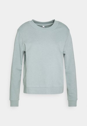 Vaaleanvihreä, pitkähihainen collegepaita, jossa on pyöreä pääntie ja resorit hihansuissa. Paidan materiaali on pehmeää ja malliltaan suora, ja se on minimalistinen yksityiskohdiltaan.