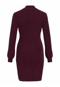 Robe en tricot bordeaux à manches longues, texture côtelée et silhouette ajustée. Elle présente un col montant et des fentes sur les côtés à l'ourlet.