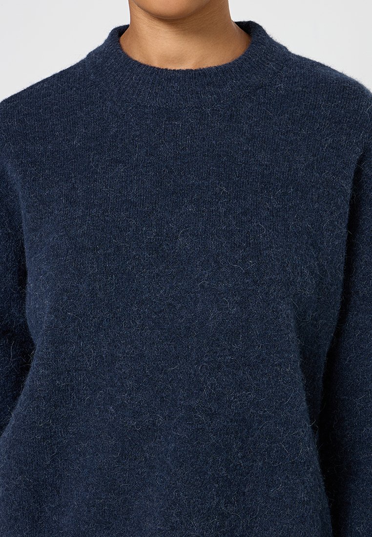 Marineblauer Wollpullover mit rundem Ausschnitt. Weiche, strukturierte Oberfläche, mit lockerer Passform und sichtbarem Strickmuster.