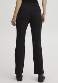Zwarte, elastische broek met een rechte pijp, voorzien van een platte tailleband en twee achterzakken. Het materiaal lijkt zacht met een gladde textuur.