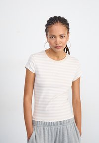 Trumpas rankovėmis, prigludęs mar�škinėliai šviesiai rožinės ir baltos juostelės. turi apvalų kaklą ir subtilų Nike logotipą ant priekinės pusės. Minkšta audinio tekstūra.