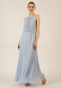 Vaaleansininen pleatattu maksimekko, jossa on olkaimettomat muotoiluelementit, kerroksellinen bodice ja valuvat hameet. Sileä pinta, jossa on hillitty kiilto. Hopeiset hihnat näkyvissä.