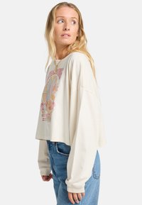 Cream-colored cropped sweatshirt with long sleeves featuring a colorful graphic design of plants and flowers on the front. Cotton material.