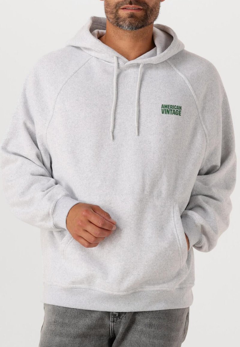 Hoodie gris clair en matière douce, doté d'une poche kangourou, d'une capuche avec cordon de serrage et du logo vert "American Vintage" sur la poitrine.