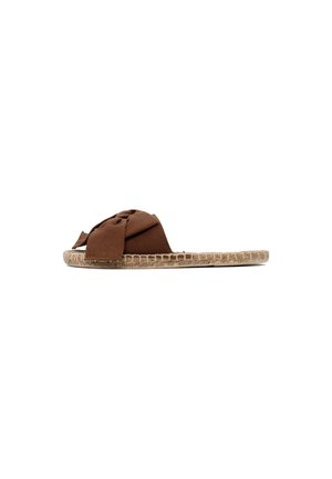 Sandalo slip-on in tessuto marrone con suola piatta intrecciata e ampia fascia annodata sulla parte superiore, fotografato su sfondo bianco.