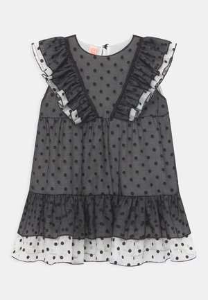 Czarna sukienka w grochy z przezroczystym materiałem, falbanistymi rękawami, dekoltem w serek i warstwowym dołem z białymi grochami. Zapięcie z tyłu w kształcie klucza.