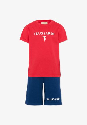 Czerwona koszulka z krótkim rękawem z napisem "TRUSSARDI" i białym logo, zestawiona z granatowymi szortami z napisem "TRUSSARDI" na lewej nodze.