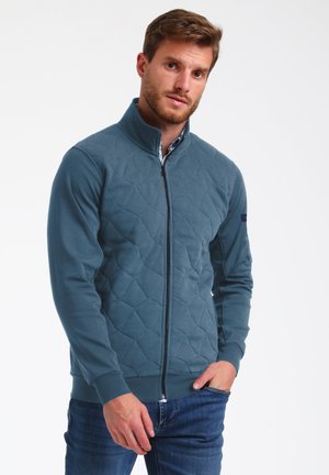 Quilted zip-up jacket in teal, featuring a textured diamond pattern, ribbed cuffs, and a contrasting inner collar. Slim fit design.