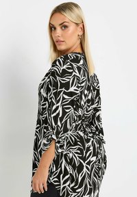 Blusa con motivo a righe bianche e nere, con un design floreale, dotata di maniche a tre quarti, vita annodata e tessuto testurizzato.