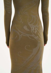 Oliwkowa sukienka z długim rękawem z fakturowanym srebrnym wzorem w kręcone wzory, dopasowany kształt oraz gładkie wykończenie materiału.