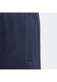 Navy blue sweatpants featuring a textured fabric, elastic waistband, and side pocket with a subtle seam detail.