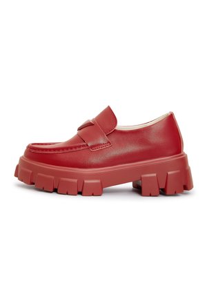 Punaiset loafersit, jotka on valmistettu sileästä synteettisestä materiaalista, leveällä hihnalla, paksulla chunky-pohjalla ja texturoitua yksityiskohtaa päällisessä.