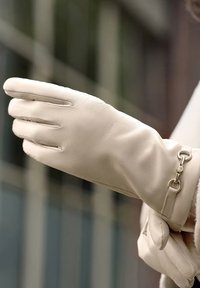 Beige leren handschoenen met gebogen vingers en een gladde textuur, voorzien van een metalen accent bij de pols voor een stevige sluiting.