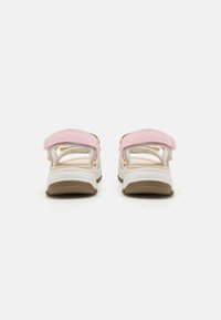 Rosa strappy sandaler med hvite såler, som har justerbare borrelåsremmer og en teksturert gummi yttersåle. Lett og åpen design.