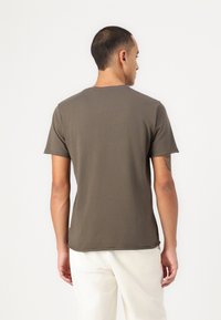 Olivegrünes T-Shirt mit kurzen Ärmeln aus einem weichen Stoff, mit Rundhalsausschnitt und lockerer Passform. Glatte Textur mit einem einfachen, klaren Design.