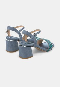 Blauwe suède hoge sandalen met een stevige blokhak, met een versierde band met turkoois en zilveren accenten. Verstelbare enkelgesp.