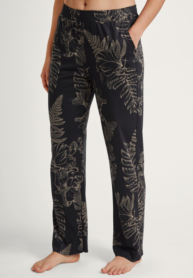 Zwarte pyjamabroek met een overal floralen en varenpatroon in goud. Gemaakt van zachte stof met een elastische tailleband en zijzakken.