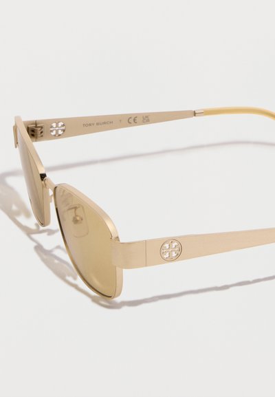 Ορθογώνια γυαλιά ηλίου σε χρυσό τόνο με χρωματισμένους φακούς και κυκλικό λογότυπο στις πλευρικές πλάκες, εμφανίζονται σε λευκό φόντο.