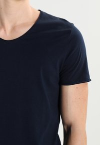 Mörkblå bomull t-shirt med kort ärm och rund halsringning. Slät textur med subtila sömnadsdetaljer.