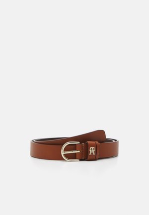 Ceinture en cuir marron avec boucle argentée et petit logo double H doré sur la passant, posée enroulée sur une surface blanche.