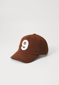 Cappello marrone con visiera curvata, caratterizzato da un '9' ricamato in bianco sulla parte anteriore. Realizzato in un tessuto testurizzato con dettagli cuciti.