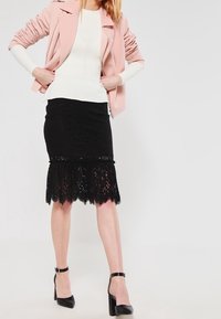 Rosa Kunstlederjacke, weißes geripptes Top, schwarzer Bleistiftrock aus Spitze mit gewelltem Saum und schwarze High Heels mit Knöchelriemen.