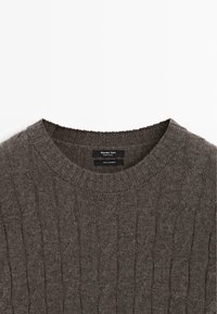 Maglione in cashmere a trecce marrone con colletto a girocollo a coste e etichetta Massimo Dutti visibile all'interno del colletto.