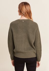 Olivgrüner, gerippter Pullover mit rundem Ausschnitt, oversized Passform, fallenden Schultern und dekorativem Knopfdetail am Rücken.