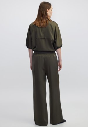 Olijfgroen outfit met een losse top met korte mouwen en wijde broekspijpen, beide in glad, glanzend stof met een elastische tailleband.