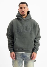 Donkergroene hoodie van zachte stof, oversized pasvorm, met een voorste kangoeroezak. Heeft verhoogde letters "BLCK BNNS" over de borst, ribgebreide manchetten en zoom.