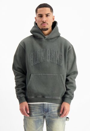 Dark green hoodie, soft fabric, oversized fit, front kangaroo pocket. Features raised lettering "BLCK BNNS" across chest, ribbed cuffs and hem.
